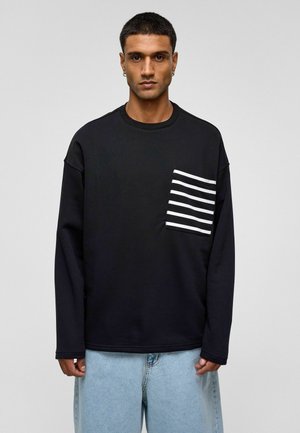 Zwarte sweatshirt met lange mouwen, een ronde hals en een voorkantzak met witte horizontale strepen. Zachte textuur, losse pasvorm en casual ontwerp.