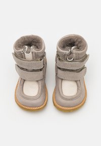 Bottes en cuir gris avec deux bandes velcro, doublure en fourrure douce, bout arrondi et semelle en caoutchouc beige clair.