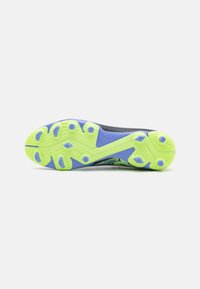 Suola di scarpa da calcio con parte superiore testurizzata nera e verde, suola in gomma fluorescente gialla e blu e vari tacchetti per la trazione.