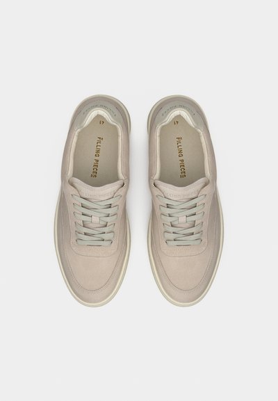 Μπεζ σουέντ αθλητικά παπούτσια με γκρι κορδόνια, στρογγυλεμένη μύτη και μαλακή επένδυση. Διακριτικό λογότυπο στα πλάγια και στο εσωτερικό. Επίπεδη σόλα από καουτσούκ.