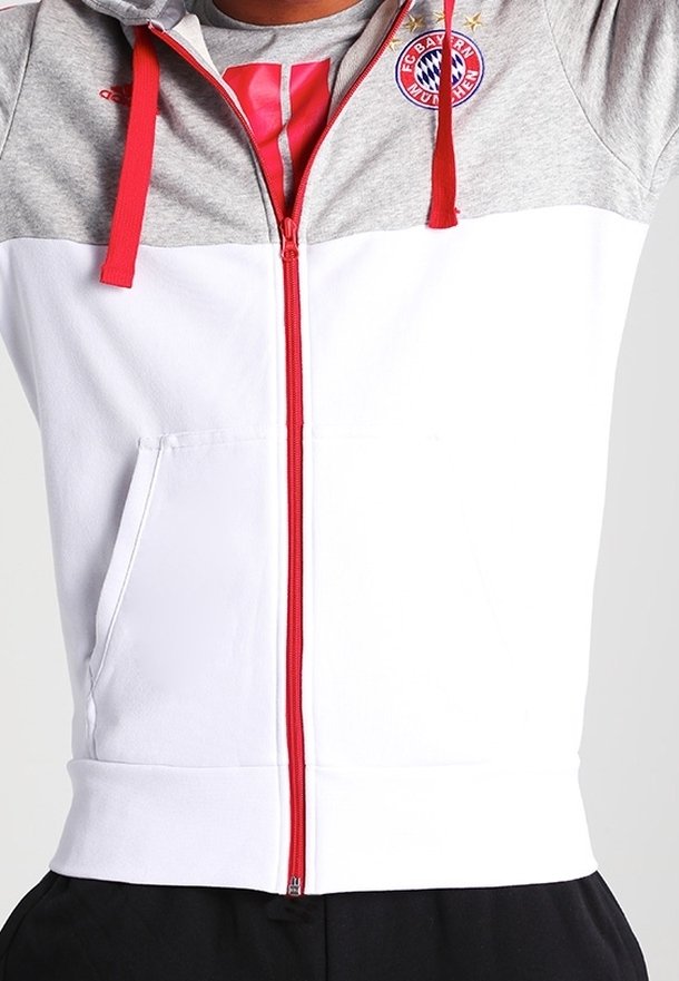 Haut de sweat zippé gris et blanc avec des accents rouges. Logo du Bayern Munich sur la poitrine et poche avant. Tissu doux, coupe athlétique.