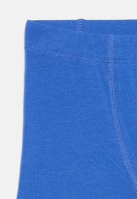 Blue cotton fabric with a smooth texture and stitched detailing along the edges. Features a wide waistband for comfort.