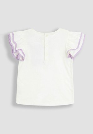 Balta kokvilnas krekls ar īsām volāniem piedurknēm, kurām ir lavandas akcenti, aizmugurējais pogu aizdare un vienkārša, taisna griezuma konstrukcija.