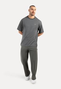 Grå bomulds T-shirt med rund hals, korte ærmer og et lille logo. Sammen med løse, olivengrønne bukser og hvide sneakers.