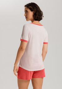 Camisa de manga corta rosa con acentos color coral en el cuello y las mangas, combinada con pantalones cortos coral a juego. Diseño de tela simple y suave.