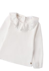 Blusa bianca a maniche lunghe con colletto arricciato e piccole pietre decorative. Presenta una chiusura sul retro e un'emblema del marchio sull'orlo.