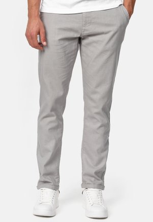 Pantalones de algodón gris claro con un ajuste slim, diseño de pierna recta y bolsillos laterales, combinados con zapatillas blancas para un look casual.