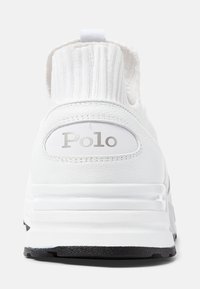 Baskets blanches avec un col en tricot côtelé, tige en cuir et semelle en caoutchouc noir. Présente un logo "Polo" en argent sur le passant du talon.