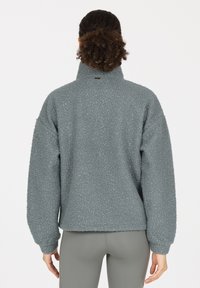 Fleece-Pullover aus weichem, strukturiertem Grau mit hohem Kragen und überschnittenen Schultern. Verfügt über gerippte Bündchen und ein gesticktes Logo am Hals.