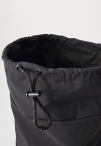 Black fabric bucket bag with a drawstring closure, featuring a smooth texture and reinforced stitching along the top edge.