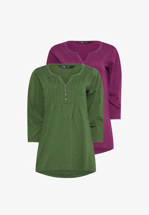 Two long-sleeve tunics: one in green with a button placket and pleats, and one in purple, both featuring soft fabric and rounded hems.