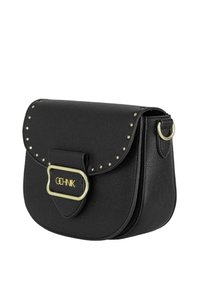 Czarna skórzana torba na ramię z klapą, złotymi elementami oraz odznakami na krawędzi. Posiada zapięcie z przodu z detalem logo.