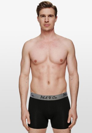 Schwarze Boxershorts mit einem grauen elastischen Bund, auf dem der Text "Phil & Co" in Schwarz steht. Glatte Textur und enganliegendes Design.