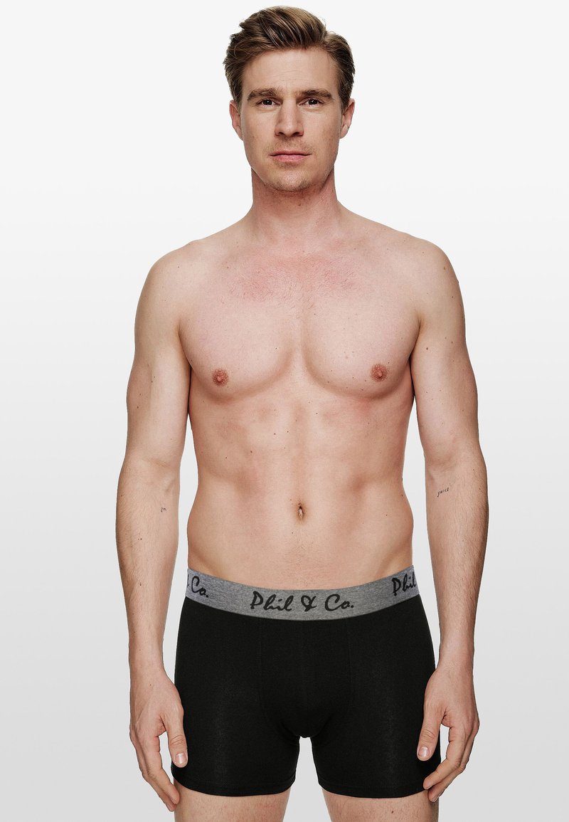 Svarta boxershorts med en grå elastisk midjena som har texten "Phil & Co" i svart. Slät textur och åtsittande design.