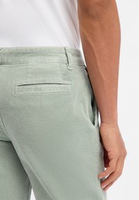 Παντελόνια από βελουτέ ύφασμα σε ανοιχτό πράσινο χρώμα με κάθετη ραβδώσεις, διαθέτουν πίσω τσέπη και μικρή ετικέτα «BOSS» κοντά στη μέση.