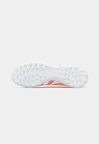 Suela de zapatilla deportiva blanca con un patrón de agarre prominente, que presenta acentos rojos y un diseño de tres rayas. Texto "PREDATOR" en relieve en el costado.