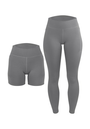 Person trägt graue Leggings mit hohem Bund und ein passendes Croptop, steht barfuß vor einem schlichten hellen Hintergrund.