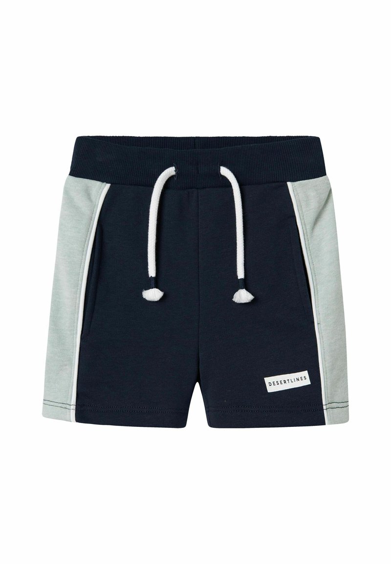 Pantaloni shorts blu navy scuro con pannelli laterali verde chiaro, vita elastica, cordoncino bianco e una piccola etichetta bianca che riporta la scritta "DESERT LINES".