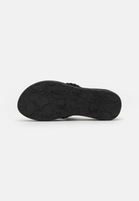 Semelle noire avec motif floral texturé et logo. Bords lisses, forme légèrement courbée et design de talon renforcé pour la durabilité.