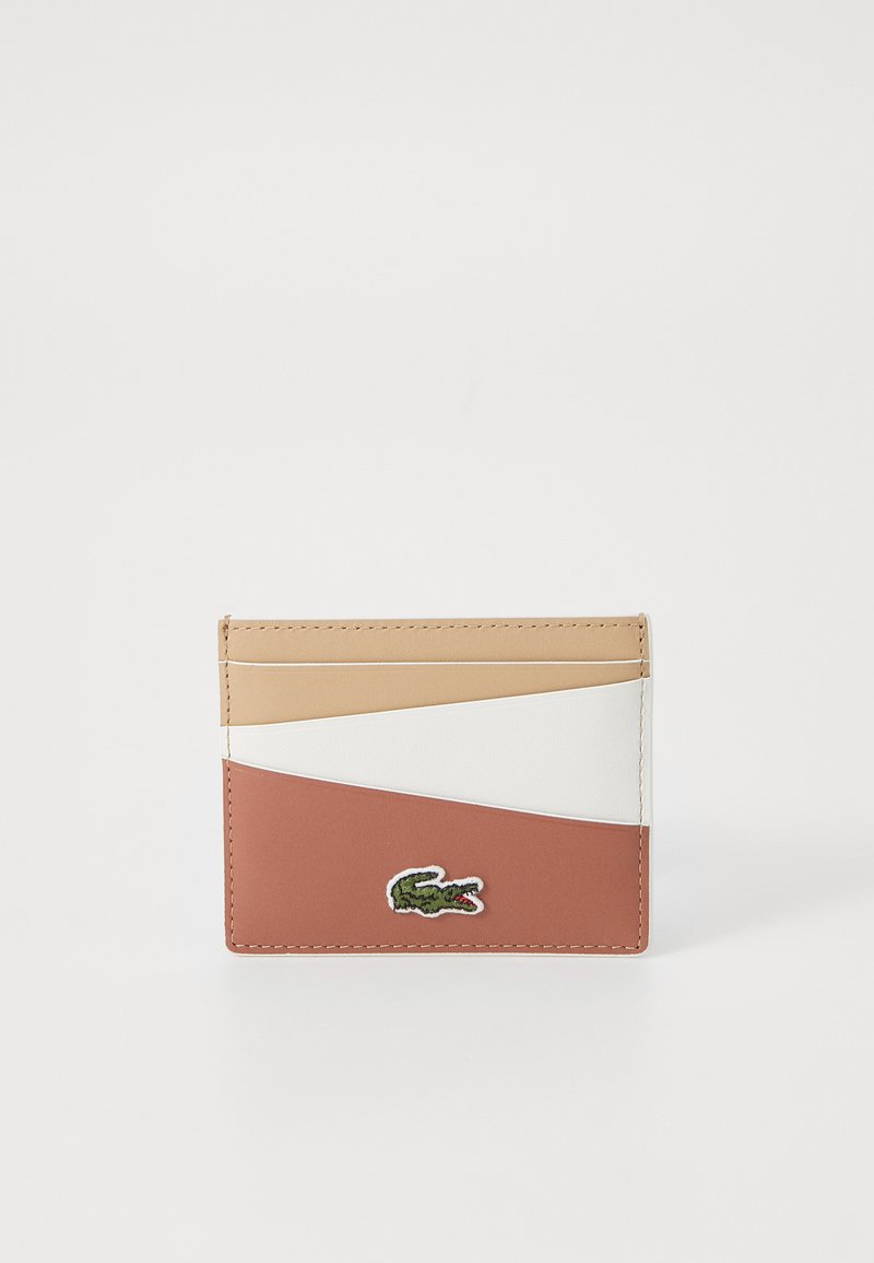 Cardholder made of textured leather in beige, white, and terracotta. Features diagonal color blocks and an embroidered green crocodile logo.