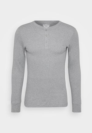 Camisa henley de manga larga gris, hecha de algodón, con un escote redondo, tres botones en la parte delantera y puños acanalados.