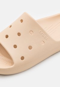 Lichtbeige schuifsandaal van textuurfoammateriaal, met ventilatiegaten en een eenvoudig ontwerp met een geribbelde voetbed.