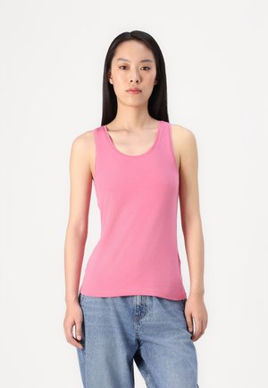 Rosa utenermed topp i lett stoff, med rund hals og slim fit. Kombinert med løstsittende blå denimjeans.