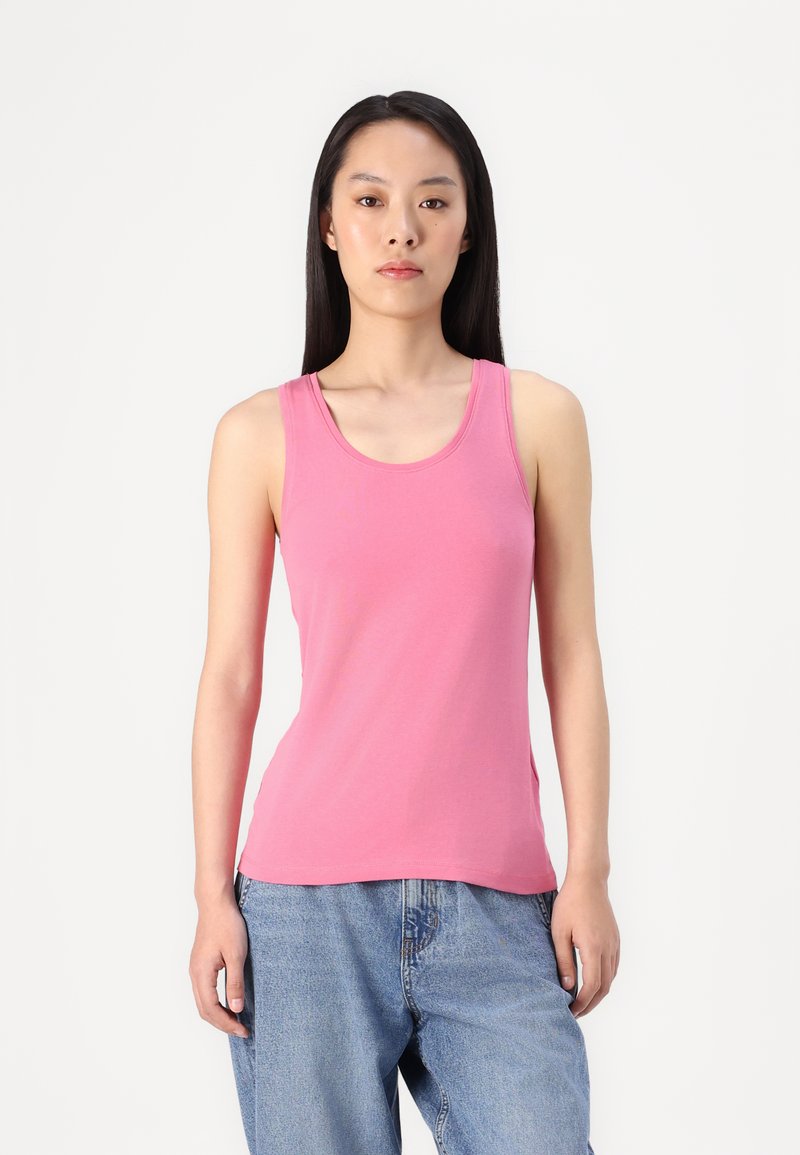Top sin mangas de color rosa en tela ligera, con escote redondo y corte ajustado. Combinado con unos vaqueros de denim azul de corte holgado.