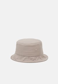 Beige bøttehatt laget av myk bomull, med rund krone, bred slapp brem og subtil sømdetalj.
