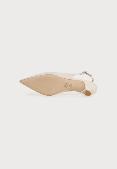 Chaussure slingback beige à bout pointu vue de la semelle, avec un talon bas épais et une bride à la cheville munie d'une petite boucle.