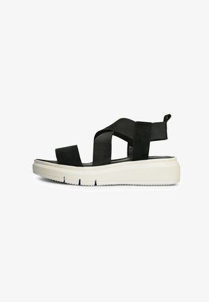 Black suede sandal featuring cross-stitched straps, a white thick sole, and a pull tab at the heel. Durable rubber outsole for grip.