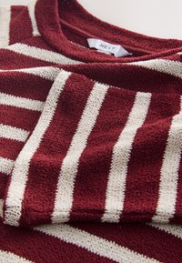 Maglione a righe bordeaux e crema con tessuto lavorato a maglia strutturato; presenta una scollatura rotonda e un'etichetta cucita all'interno del colletto.