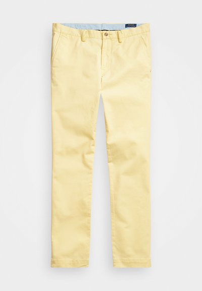 Żółte bawełniane chinosy z prostą nogawką, z zapięciem na guzik i jasnoniebieskim wykończeniem wewnętrznym pasa. Gładka tekstura i minimalne detale.