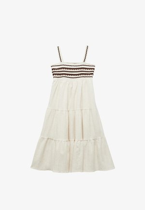Robe blanche à volants avec un tissu texturé, dotée de fines bretelles et d'un corsage brodé marron.