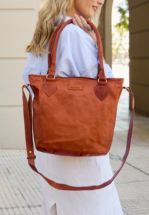 Sac fourre-tout en cuir marron avec deux poignées, une bandoulière ajustable et des accents surpiqués. Présente une forme rectangulaire et une surface texturée.