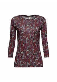 Lång ärmad topp i genomskinligt tyg med ett flerfärgat abstrakt mönster av röd, vit och lila mot en mörk bakgrund. Rund halsringning.