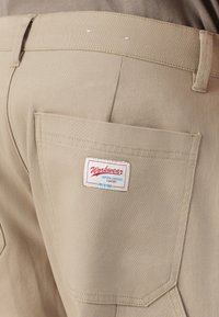 Beige workwear pants shown from the back, highlighting a pocket with a white label reading "Workwear uniform-inspired comfort Only & Sons."