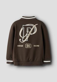 Bruine sweatshirt met witte details, voorzien van een groot geborduurd "P" en de tekst "VINTAGE 86 RACING" op de achterkant. Zachte textuur, sportief ontwerp.