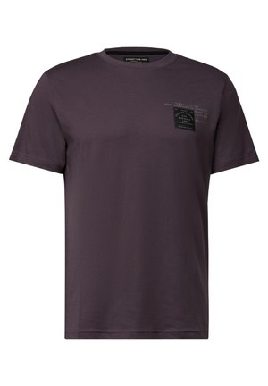 T-shirt en coton violet foncé à manches courtes, col rond, avec une petite étiquette noire sur la poitrine portant un texte et des graphiques blancs.