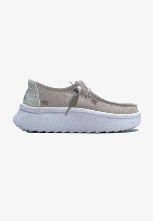 Sneaker in tela grigia chiara con un tacco testurizzato, suola bianca maculata e forma arrotondata; presenta lacci decorativi e un marchio.