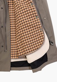Giacca esterna grigia con fodera interna a motivo houndstooth testurizzato in marrone e beige, dotata di bottoni e di uno strato di pile liscio alla base.