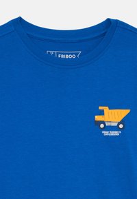 Modra bombažna majica s krožnim izrezom, ki ima grafiko rumenega tovornjaka in besedilo "TOVORNJAKI ZA DUMP IN SANJE" v belem.