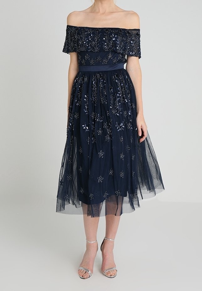 Námořnické off-shoulder šaty s přiléhavým korzetem, vyšívanými květinovými detaily a vrstvenou tylovou sukní. Obsahuje volný pas.