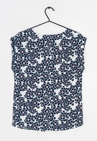 Blouse à manches courtes florale en bleu marine, blanc et rose, avec un col rond et une coupe ample en tissu texturé.