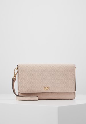 Pochette-bracelet rose blush Michael Kors avec motif du logo MK en relief, emblème MK doré et bride détachable, posée sur une surface blanche.