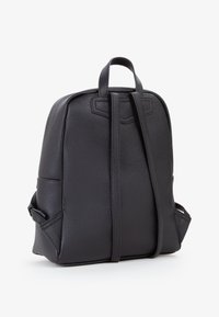 Zaino in pelle nera con un design strutturato, finitura testurizzata, doppi manici superiori e spallacci regolabili, dotato di una tasca laterale discreta.