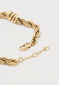 Κολιέ με χρυσή αλυσίδα, χοντρούς στριφτούς κρίκους και κούμπωμα με ρίγες κόκκινου, λευκού και μπλε, μαζί με προσαρμόσιμη επέκταση αλυσίδας.