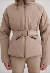 Beige pufferjakke med bælte i taljen, lynlåslommer og høj krave. Fremstillet af et glat, vandafvisende materiale.