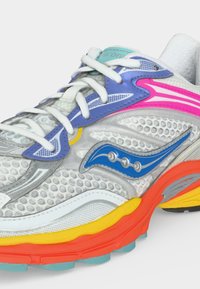 Λευκό πλεκτό παπούτσι τρεξίματος με μπλε, ροζ, κίτρινες και πορτοκαλί λεπτομέρειες, λευκά κορδόνια και μπλε λογότυπο Saucony στο πλάι.
