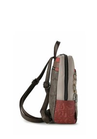 Vertikaler Rucksack in Beige und Braun mit strukturierter Oberfläche, kontrastierenden roten Akzenten, Reißverschluss und verstellbaren Gurten.